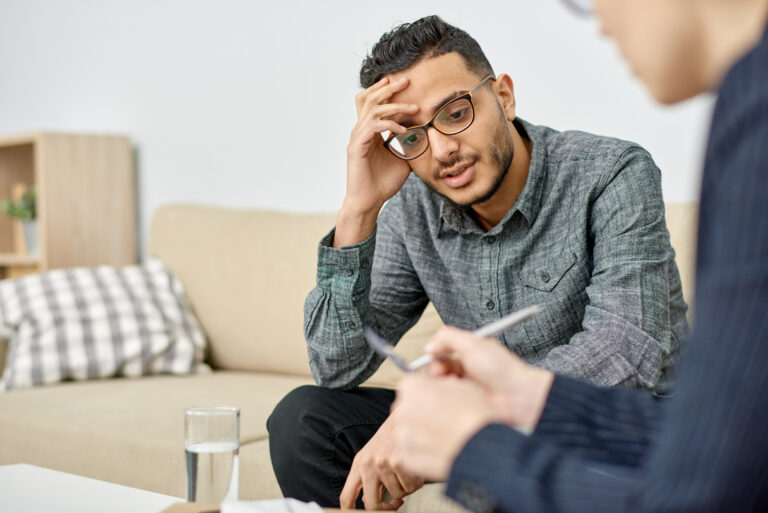 young man sat in room with psychologist during therapy session